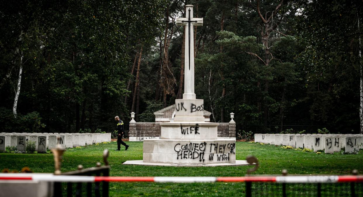 A police officer walks past graves which have been vandalised with graffiti, and a large swastika was daubed on the inner wall of the chapel in the British World War II Commonwealth Graves cemetery in Mierlo, east of Eindhoven, Netherlands, on September 13, 2019. (Photo by Rob Engelaar / ANP / AFP) / Netherlands OUT        (Photo credit should read ROB ENGELAAR/AFP/Getty Images)