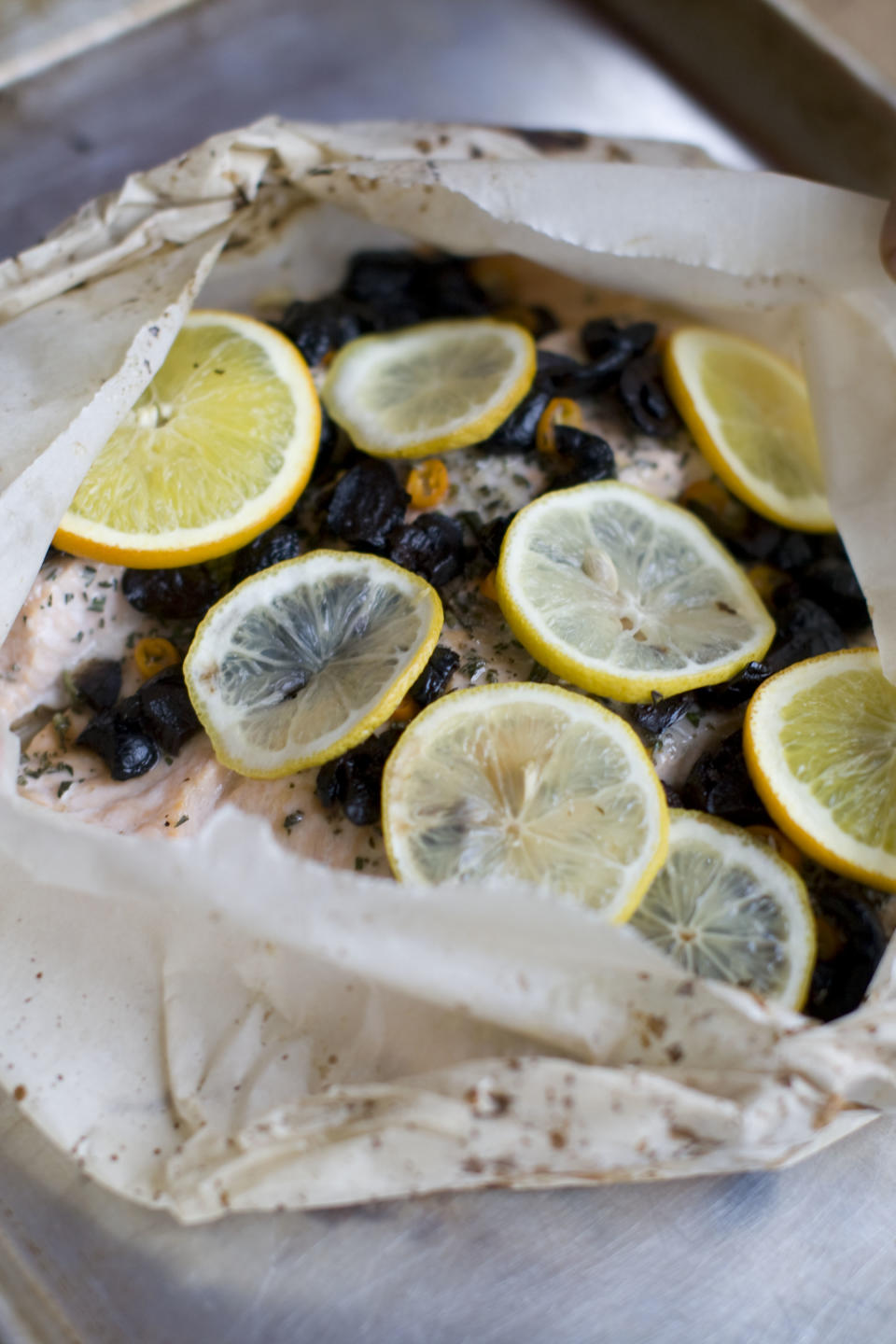 This Dec. 2, 2013 photo shows salmon baked in a bag with citrus, olive and chilies in Concord, N.H. The bag keeps the flavor and moisture trapped inside during cooking, allowing the juices from the fish and the other ingredients to mingle and become a wonderful sauce. (AP Photo/Matthew Mead)