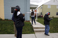 In this March 31, 2020, photo, Charlie Gussom, Jr., center, with Martha's Table, encourages a social distance of 6-feet between residents, demonstrating with his arms straight out, as people stand in line to receive donated food in southeast Washington. Neighborhood deliveries are part of a new Martha's Table initiative, along with community partners, to get needed food directly to the neighborhoods they serve. Local volunteers are the tip of the spear for a grassroots community effort to keep Washington's most vulnerable neighborhoods fed during the unprecedented coronavirus crisis which has nearly shut down the American economy. (AP Photo/Jacquelyn Martin)