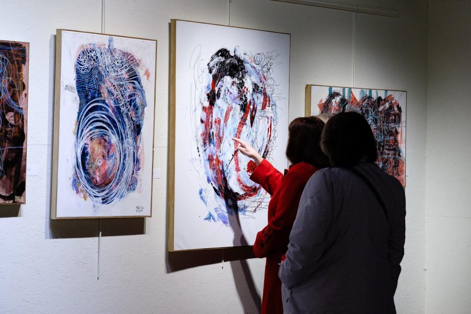 A viewer examines details in a painting by Martin Pope at a January 2024 exhibit at Orr Street Studios.