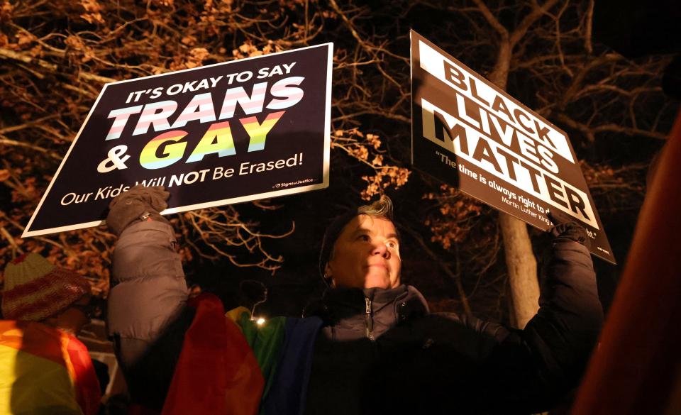 Toben Asklar holds signs during a protest outside the Stoughton School Committee meeting where the superintendent's ban on political flags in classrooms was discussed on Tuesday, Jan. 10, 2023.