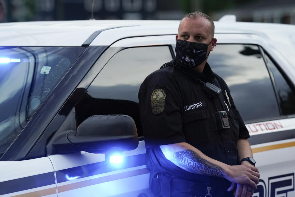 An Elizabeth City police officer watches people block an intersection after at least one Pasquotank County Sheriff's deputy shot and killed a Black man, Andrew Brown Jr., while executing a search warrant, the sheriff's office said, Wednesday, April 21, 2021, in Elizabeth City, N.C. The deputy was wearing an active body camera at the time of the shooting, said Sheriff Tommy Wooten II, who declined to say how many shots the deputy fired or release any other details, citing a pending review by the State Bureau of Investigation. (AP Photo/Gerry Broome)