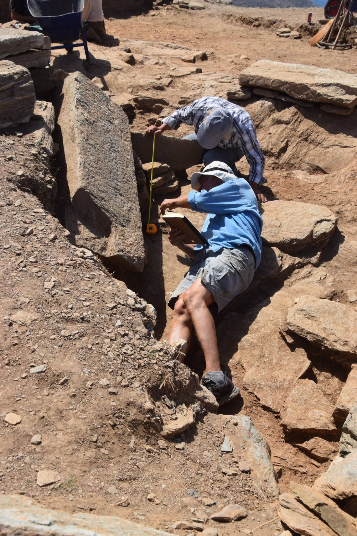 Archaeologists excavate a large slab with an inscription from the ruins of building No. 3.