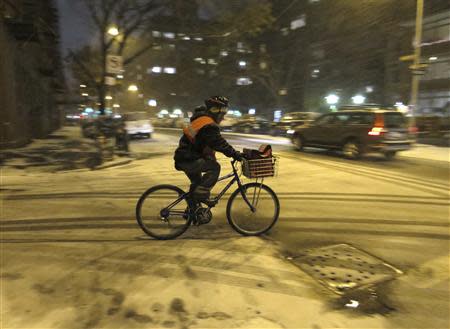 A restaurant delivery person rides his bike through the West Village neighbourhood as snow begins to fall in New York January 2, 2014. REUTERS/Gary Hershorn