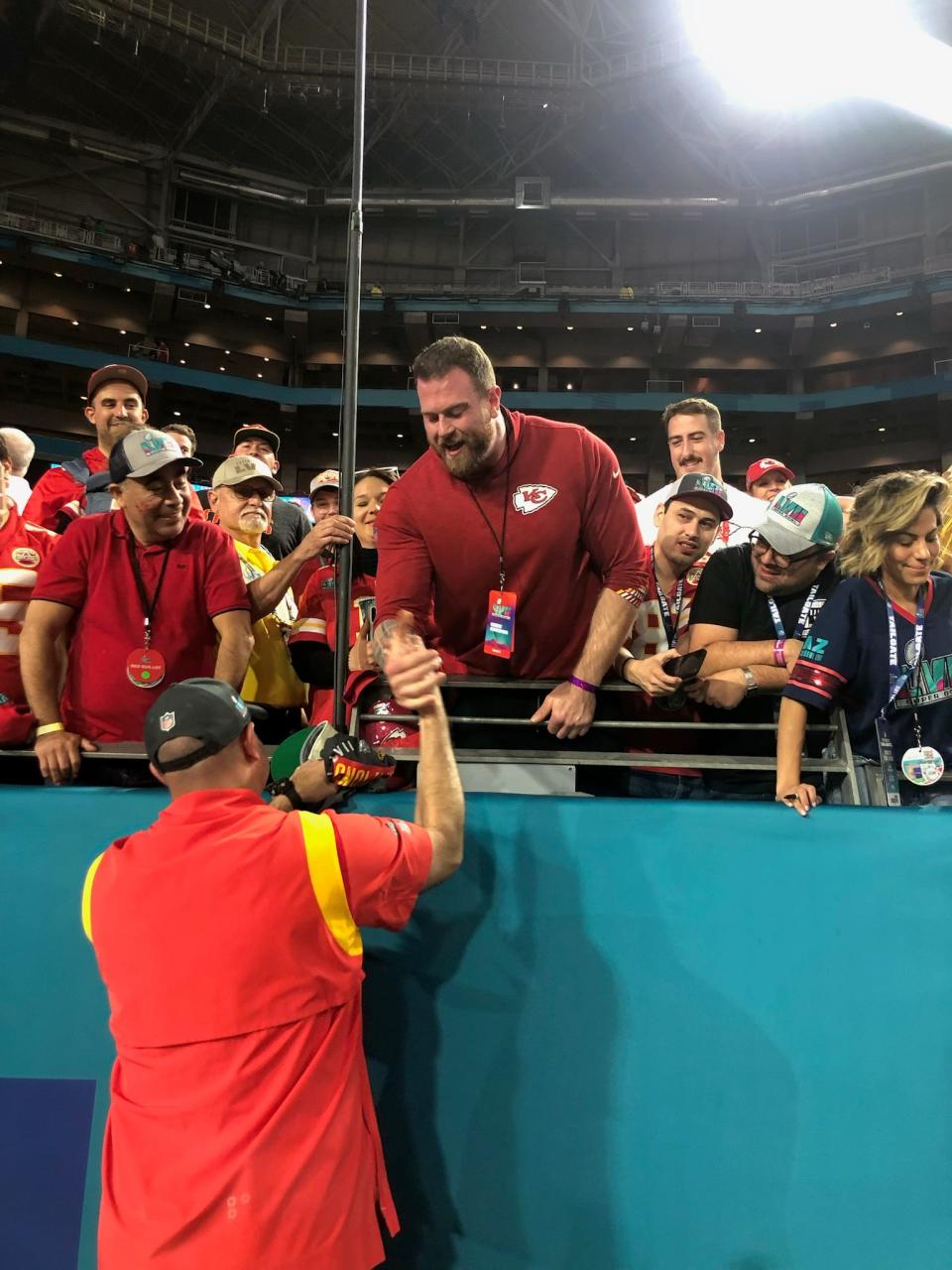 Kansas City Chiefs offensive line coach Andy Heck, bottom, greets son Jon in the stands. Andy's other son, Charlie Heck, is behind Jon in the white shirt with the mustache. Charlie is an offensive tackle with the Houston Texans.