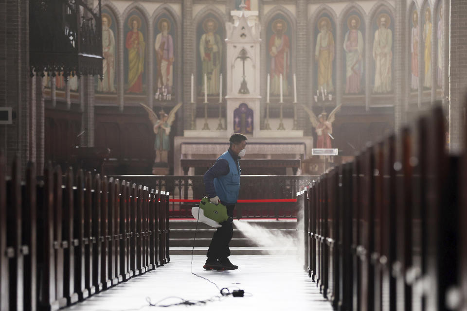 A worker wearing a face mask sprays disinfectant as a precaution against the new coronavirus at Myeongdong Cathedral in Seoul, South Korea, Wednesday, Feb. 26, 2020. The number of new virus infections in South Korea jumped again Wednesday and the U.S. military reported its first case among its soldiers based in the Asian country, with his case and many others connected to a southeastern city with an illness cluster. (Lee Ji-eun/Yonhap via AP)