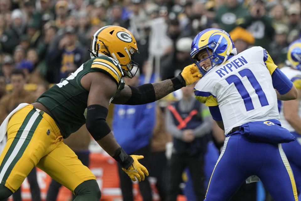 Green Bay Packers linebacker Rashan Gary (52) grabs the face mask of Los Angeles Rams quarterback Brett Rypien (11) during the first half of an NFL football game Sunday, Nov. 5, 2023, in Green Bay, Wis. (AP Photo/Morry Gash)