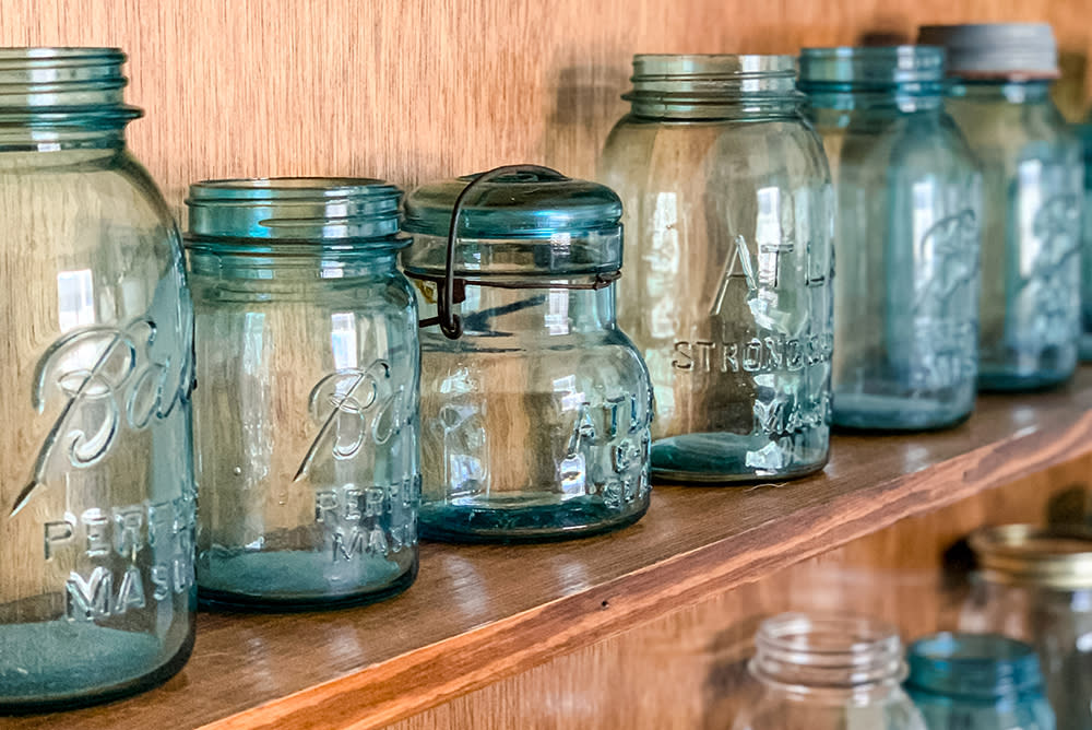 Close-up view of a vintage blue mason jar collection displayed on wooden shelves