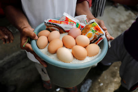 A villager holds eggs, rice and noodles during an aid distribution at the epicentre of a devastating earthquake at Lende Tovea village in Donggala, Indonesia Sulawesi island, October 6, 2018. REUTERS/Beawiharta