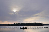 Oyster farmers Sam Dorval and Chris Burtis of Ferda Farms harvest oysters from floating crates on the New Meadows River, Sunday, April 25, 2021, in Brunswick, Maine. Oysters from the farm are being used to support an existing population in New Hampshire's Great Bay. (AP Photo/Robert F. Bukaty)