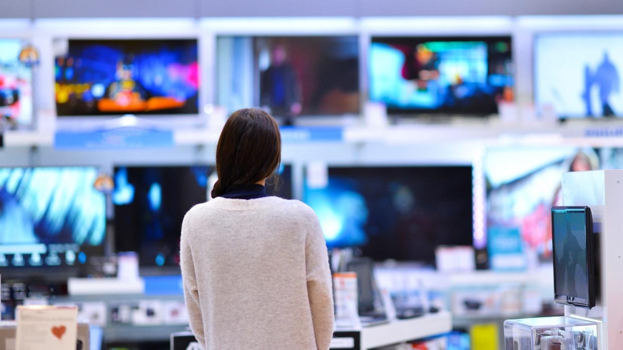 A woman looking at a wall of televisions.