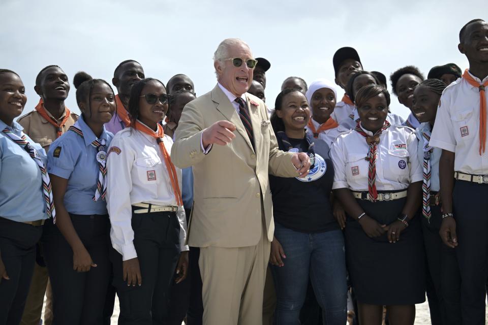 FILE - Britain's King Charles III, center gestures as he meets with Kenyan Scouts during a visit to Nyali beach in Mombasa, Kenya, Thursday, Nov. 2, 2023. King Charles III’s decision to be open about his cancer diagnosis has helped the new monarch connect with the people of Britain and strengthened the monarchy in the year since his dazzling coronation at Westminster Abbey. (Simon Maina/Pool Photo via AP, File)