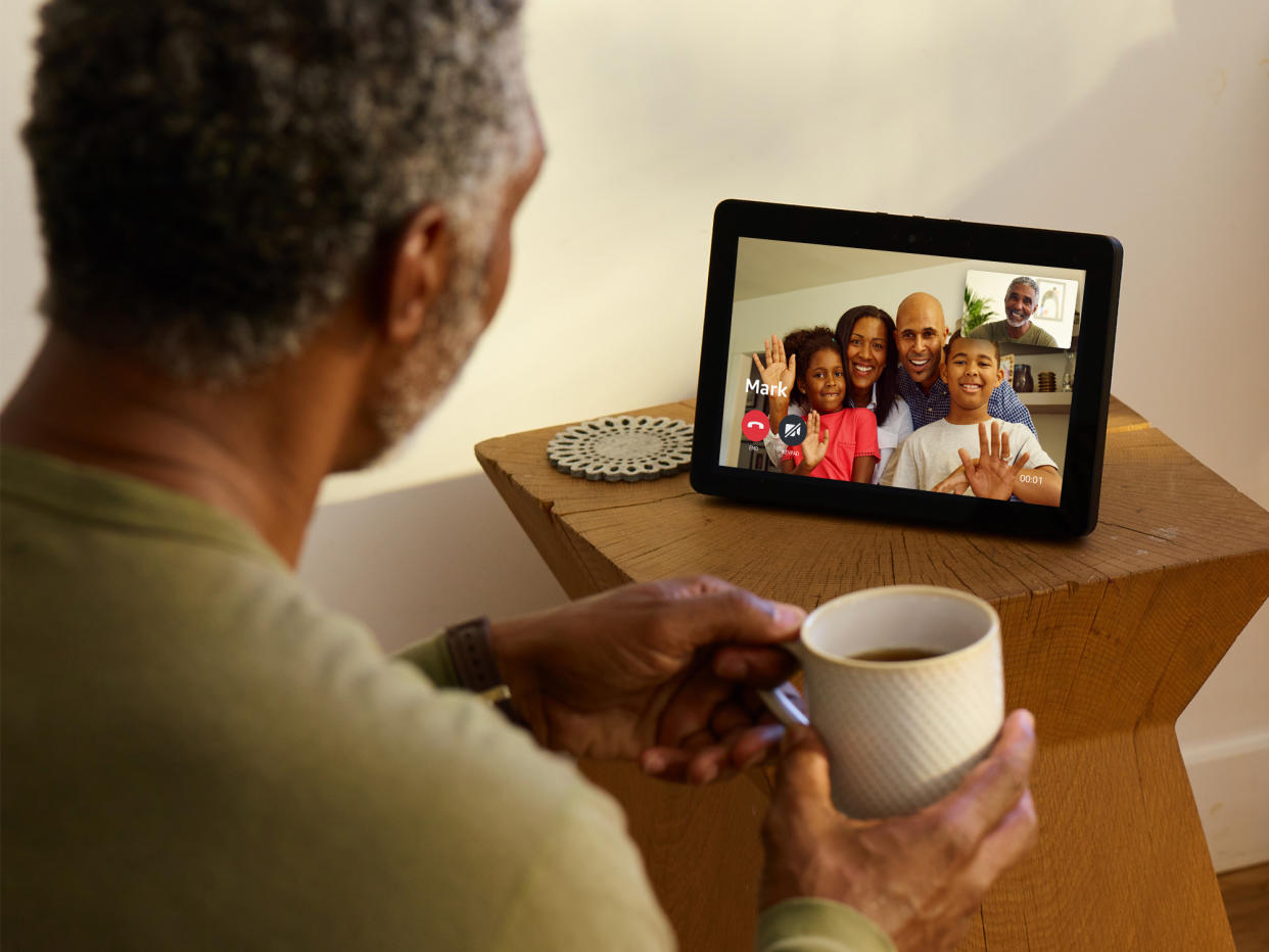  Man holding coffee mug sitting in front of Echo Show on a video call. 