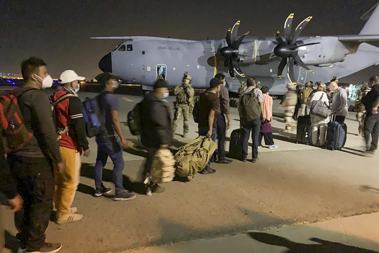 People line up to board a French military transport plane 