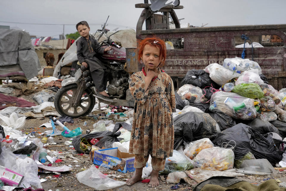 FILE - Two Afghan children stand amid piles of garbage next to their home in Kabul, Afghanistan, Monday, April 18, 2022. (AP Photo/Ebrahim Noroozi, File)