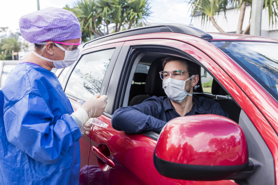 A doctor in a protective suit taking a nasal swab from a driver to test for possible coronavirus infection