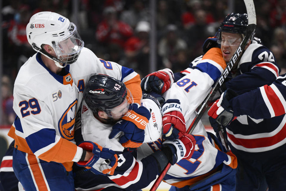Washington Capitals right wing Tom Wilson (43) and defenseman John Carlson (74) scuffle with New York Islanders center Brock Nelson (29) and left wing Pierre Engvall (18)during the first period of an NHL hockey game, Monday, April 10, 2023, in Washington. (AP Photo/Nick Wass)