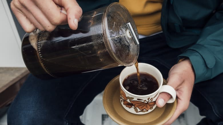 Hand pouring French press coffee into a mug