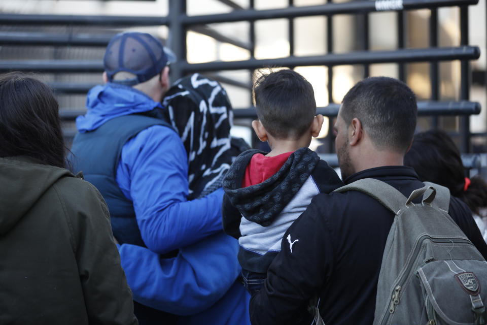 Honduran asylum seekers enter the U.S. at San Diego's Otay Mesa port of entry, as seen from Tijuana, Mexico, Tuesday, Dec. 18, 2018. Six Honduran asylum seekers spent a chilly night camped out on a tiny patch of U.S. soil at a San Diego border crossing seeking to have their claims processed. (AP Photo/Moises Castillo)