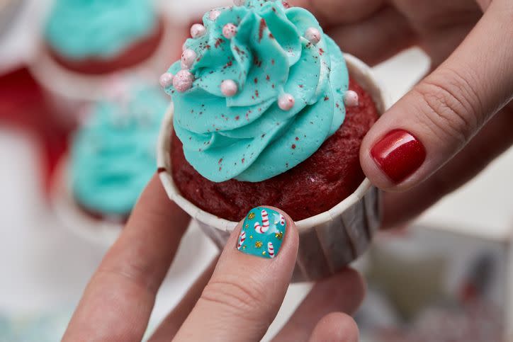 female hand with festive christmas manicure holding tasty cupcake christmas and new year treat