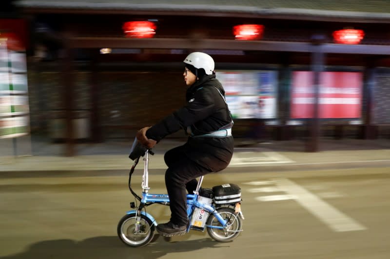 Liu Pengfei, a substitute driver of ride-hailing service platform DiDi Chuxing, rides his electric bike after driving a client's car in Beijing