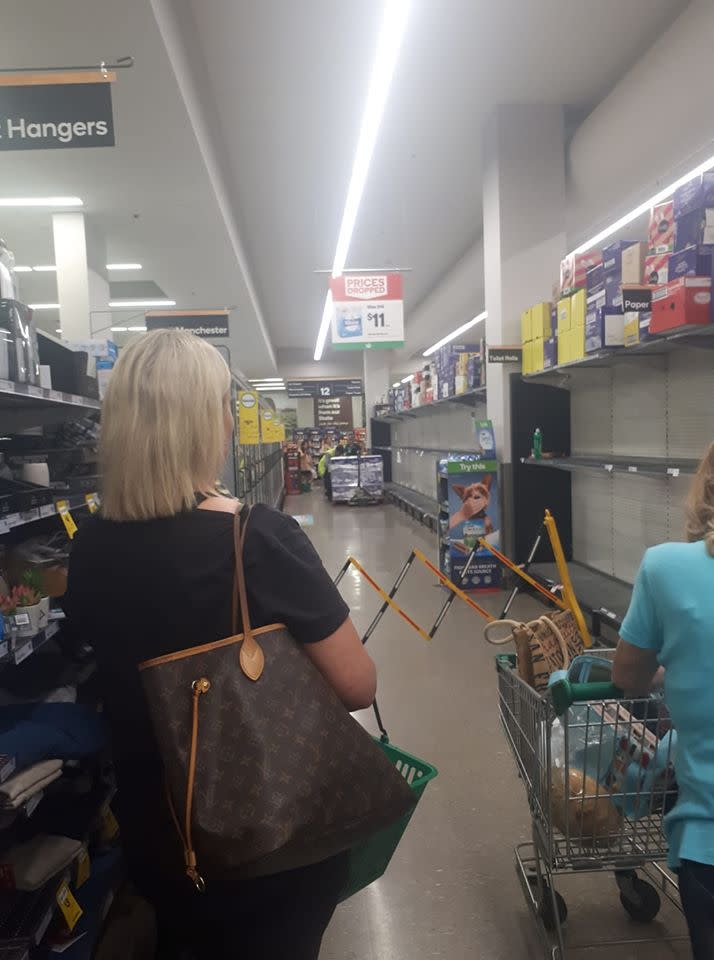 The woman shared a photo of the Woolworths putting up a barrier to allow staff to stock the shelves with toilet paper. Source: Facebook