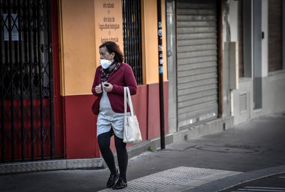 A woman wearing a protective mask carries a bag on March 26, 2020 in Paris, on the tenth day of a lockdown aimed at curbing the spread of the COVID-19 (novel coronavirus) in France. (Photo by STEPHANE DE SAKUTIN / AFP) (Photo by STEPHANE DE SAKUTIN/AFP via Getty Images)