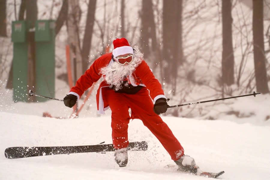 A skier dressed as Santa Claus crashes, Sunday, Dec. 10, 2023, at the Sunday River ski resort in Newry, Maine. The annual Santa Sunday event raises money for local charities. (AP Photo/Robert F. Bukaty)