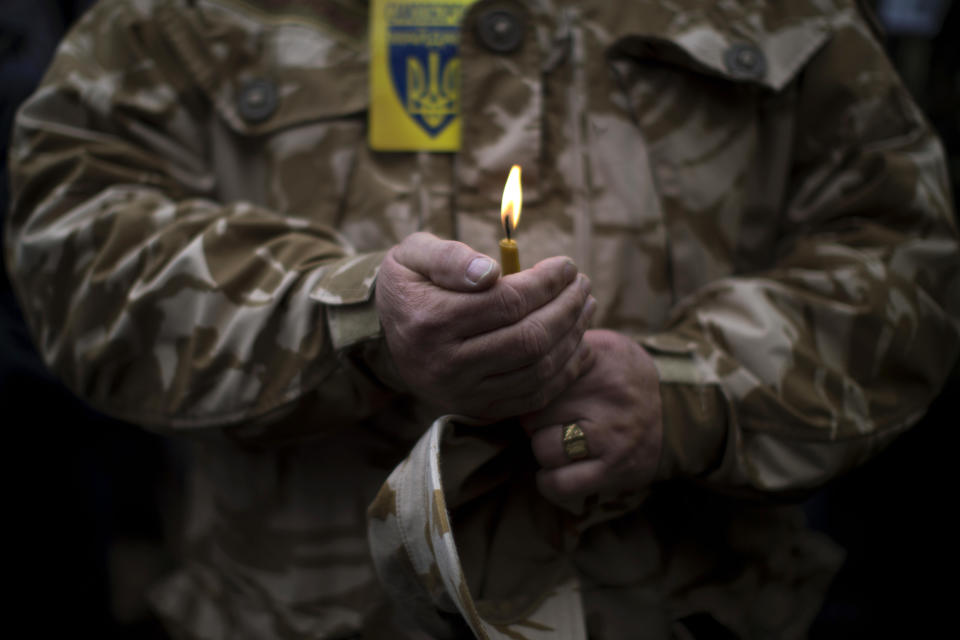 A man wearing camouflage uniform holds a candle during the funeral of Volodymyr Topiy, 59, who was found burned in the house of trade unions in Kiev's Independence Square during recent clashes with police, Ukraine, Tuesday, March 4, 2014. Vladimir Putin ordered tens of thousands of Russian troops participating in military exercises near Ukraine's border to return to their bases as U.S. Secretary of State John Kerry was on his way to Kiev. Tensions remained high in the strategic Ukrainian peninsula of Crimea with troops loyal to Moscow fired warning shots to ward off protesting Ukrainian soldiers. (AP Photo/Emilio Morenatti)