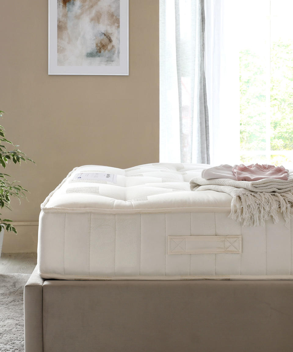 mattress in beige room with large window