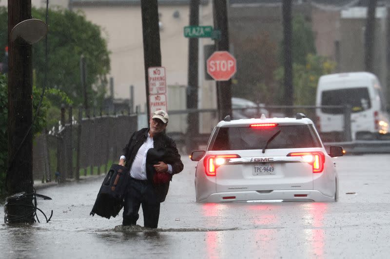 Un hombre carga sus pertenencias mientras abandona su vehículo que se detuvo en las inundaciones durante una fuerte tormenta en el suburbio de Mamaroneck en la ciudad de Nueva York en el condado de Westchester, Nueva York, EEUU