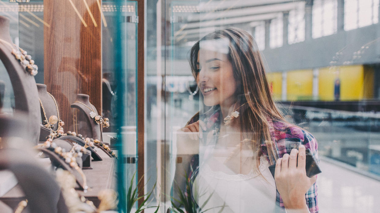 Young woman in the shopping mall looking at gorgeous jewellery on the shop window.