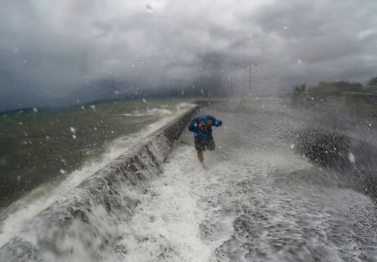 Waves spill over a wall onto a road in Legaspi in Albay province south of Manila on December 14, 2015