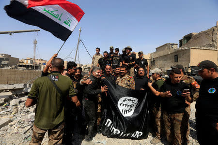Iraqi Counter Terrorism Service (CTS) hold an Islamic State flag, which they pulled down in the Old City of Mosul, Iraq July 9, 2017. REUTERS/Alaa Al-Marjani