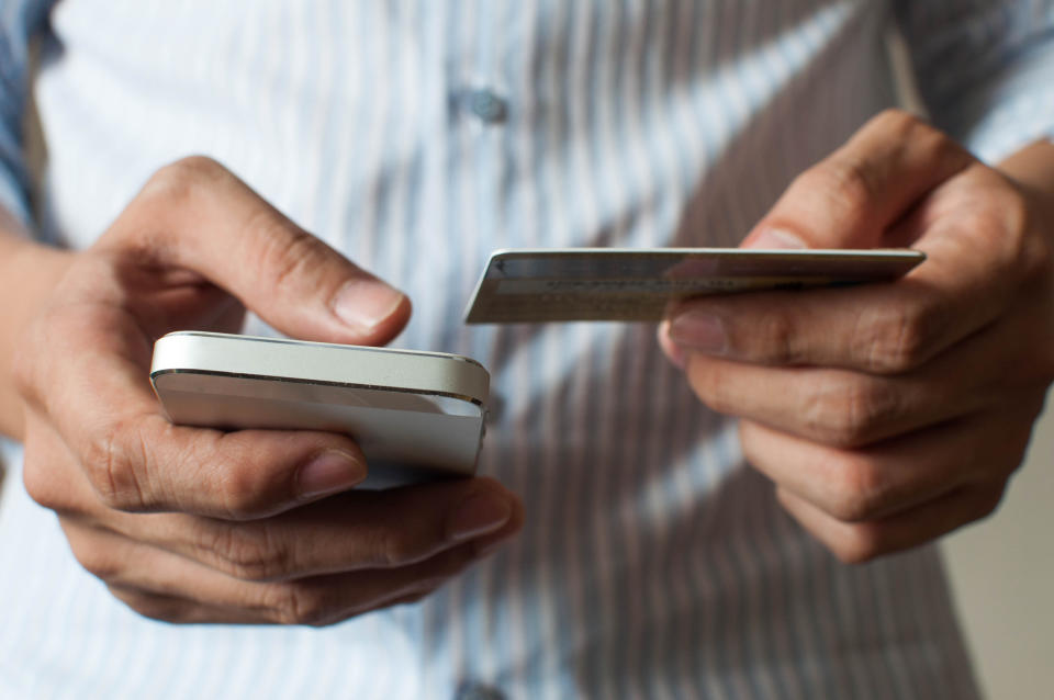 A man is buying online using his mobile phone and credit card. Source: Getty