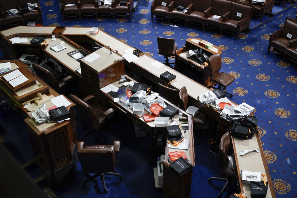 Papers and gas masks are left behind after House of Representatives members left the floor of the House chamber as protesters try to break into the chamber at the U.S. Capitol on Wednesday, Jan. 6, 2021, in Washington. (AP Photo/J. Scott Applewhite)