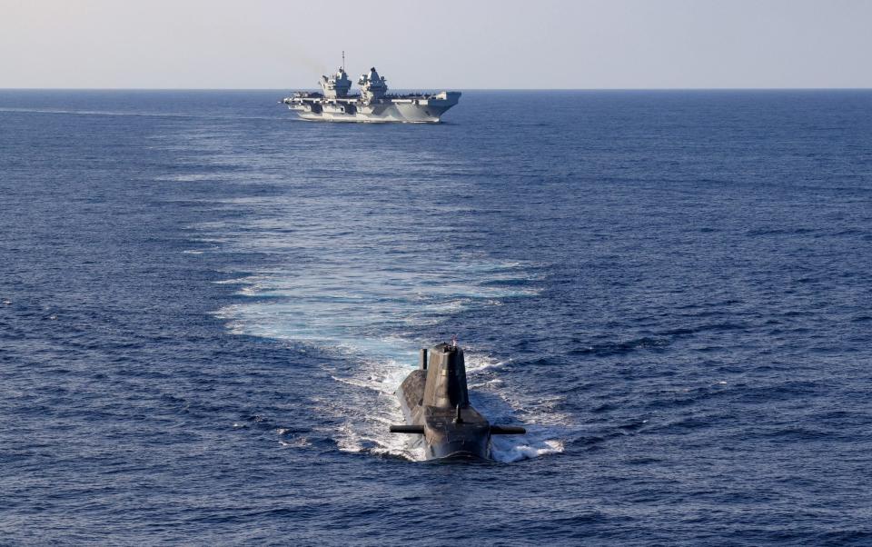 An Astute Class Submarine on the surface with HMS Queen Elizabeth in the background - Royal Navy