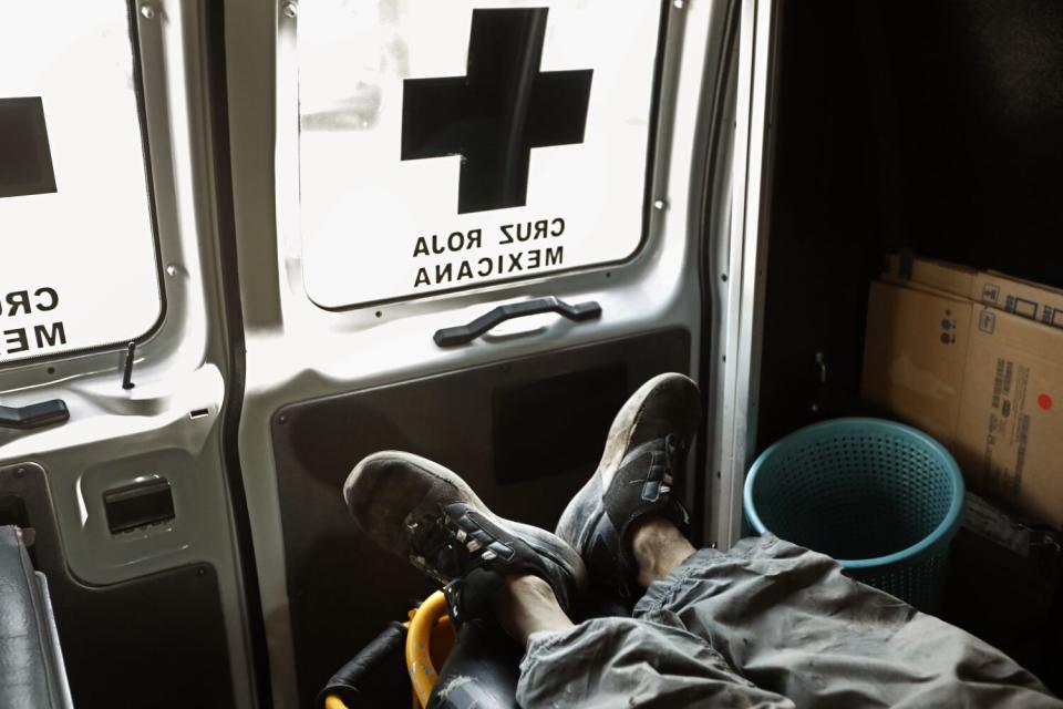 A view of the legs and feet of a person in sneakers on a gurney inside an ambulance