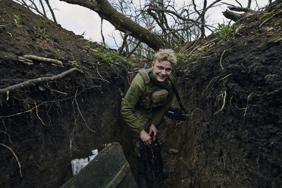 A Ukrainian soldier smiles as he stands in a trench on the frontline near Avdiivka, an eastern city where fierce battles against Russian forces have been taking place, in the Donetsk region, Ukraine, Friday, April 28, 2023. (AP Photo/Libkos)