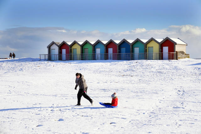 A woman pulls a child on a sledge through the snow beside the beach huts at Blyth in Northumberland. Weather warnings for snow and ice are in place across all four nations of the UK and more are expected to be issued as Arctic air sweeps across the country. Picture date: Tuesday March 7, 2023. (Photo by Owen Humphreys/PA Images via Getty Images)