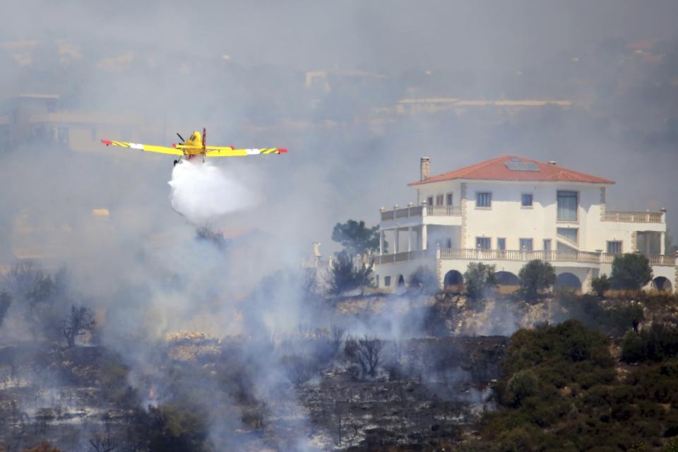 An aircraft drops water over a fire in Apesia semi-mountainous village near Limassol, southwestern Cyprus, Monday, Aug. 7, 2023. Greece on Monday dispatched two Canadair fire-fighting aircraft after a call for assistance from fellow European Union member Cyprus to help fight a blaze that has scorched miles of mountainous terrain. (AP Photo/Philippos Christou)