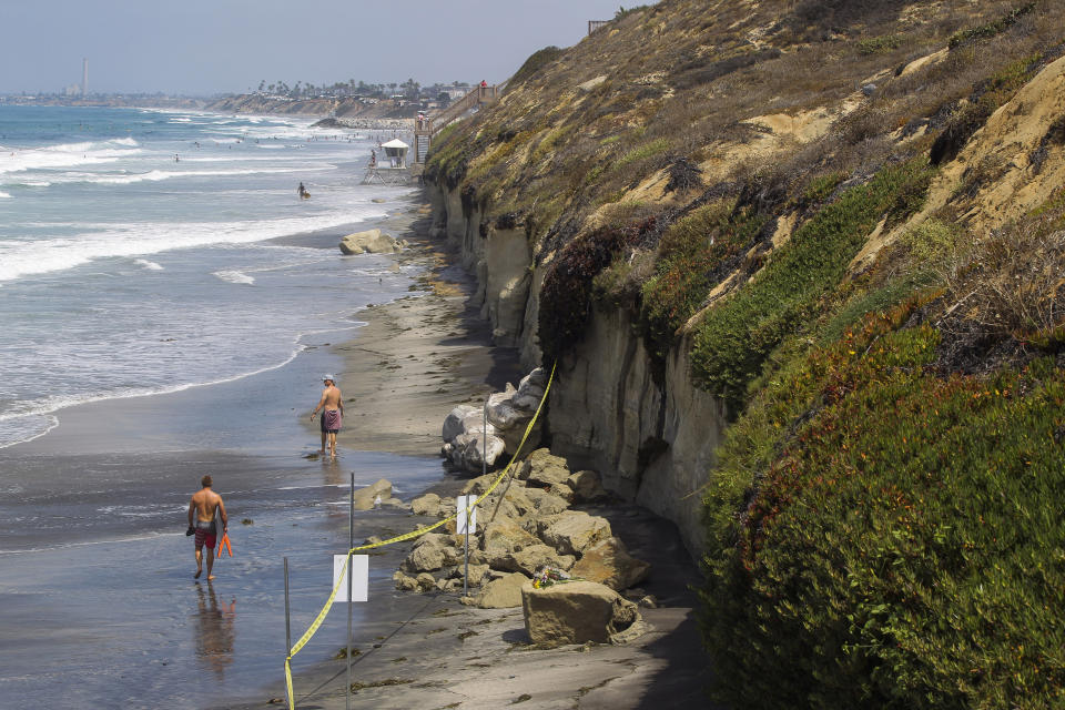 FILE - In this Aug. 3, 2019 file photo the area where a sea cliff collapsed killing three people is taped off near the Grandview Beach access stairway in the beach community of Leucadia, in Encinitas, Calif. Three family members enjoying a day at a San Diego area beach were killed Friday when a huge slab of the cliff above plunged on to the sand. The collapse has raised questions about the stability of bluffs along California's 1,000-mile (1,600-kilometer) coast. (Hayne Palmour IV/The San Diego Union-Tribune via AP,File)