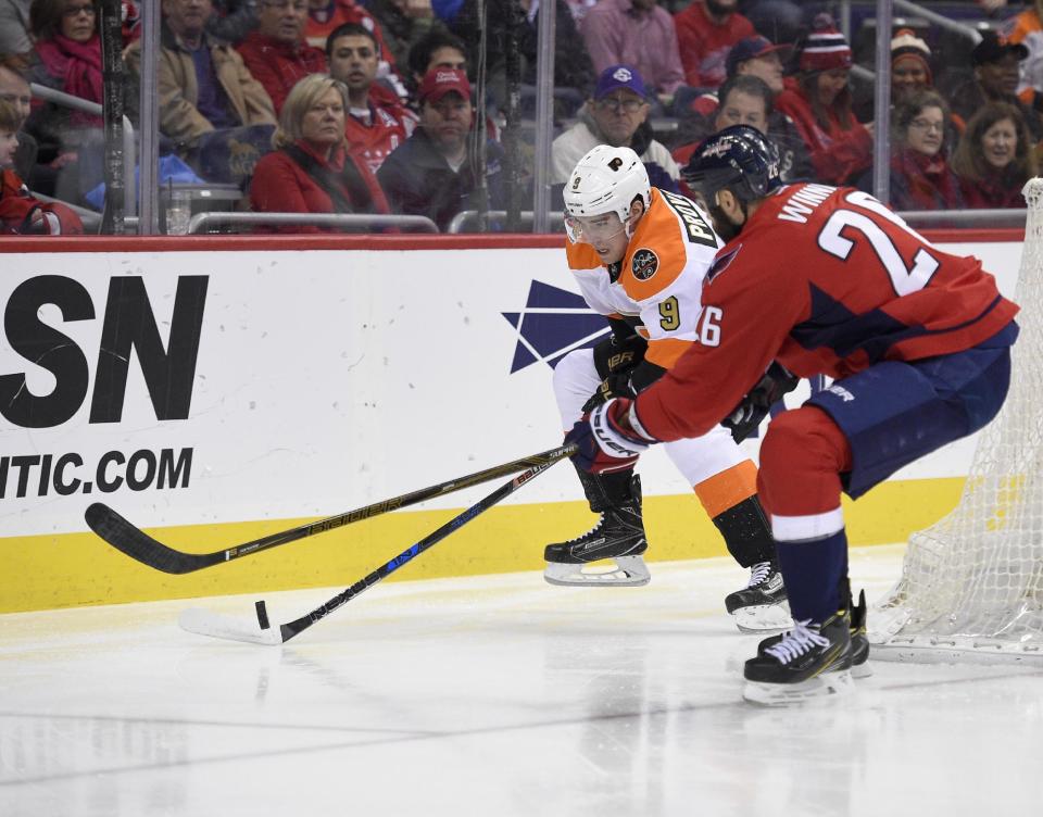 Washington Capitals left wing Daniel Winnik (26) fight for the puck against Philadelphia Flyers defenseman Ivan Provorov (9), of Russia, during the first period of an NHL hockey game, Sunday, Jan. 15, 2017, in Washington. (AP Photo/Nick Wass)