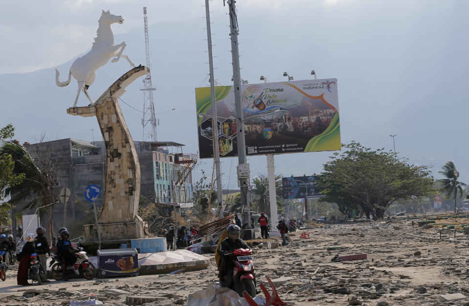 People survey the damage following a massive earthquake and tsunami at Talise beach in Palu, Central Sulawesi, Indonesia, Monday, Oct. 1, 2018. A mass burial of earthquake and tsunami victims was being prepared in a hard-hit city Monday as the need for heavy equipment to dig for survivors of the disaster that struck a central Indonesian island three days ago grows desperate. (AP Photo/Tatan Syuflana)