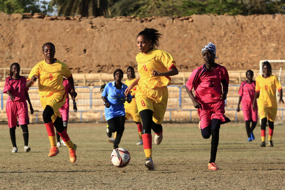 In this Wednesday, Dec. 11, 2019 photo, Sudanese al-Difaa, in yellow, and al-Sumood women teams play in Omdurman, Khartoum's twin city, Sudan. The women's soccer league has become a field of contention as Sudan grapples with the transition from three decades of authoritarian rule that espoused a strict interpretation of Islamic Shariah law. (AP Photo)