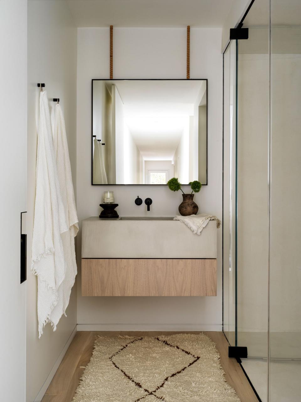 Like the others, the guest bath features a custom vanity of bleached walnut by Alexander Design, with a Cam Crawford custom mirror, matte black Vola plumbing, and a vintage Moroccan rug.