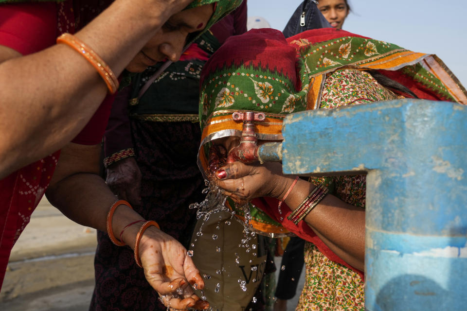 FILE - Women drink water from a public tap near the River Ganges on a hot day at Sangam in Prayagraj, Uttar Pradesh state, India, May 2, 2024. In a world growing increasingly accustomed to wild weather swings, the last few days and weeks have seemingly taken those environmental extremes to a new level. (AP Photo/Rajesh Kumar Singh, File)