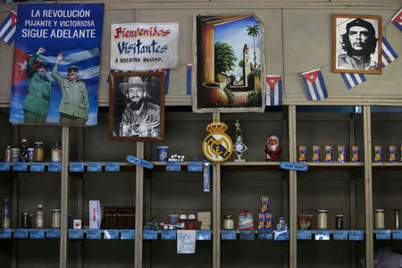 A poster showing late Cuban President Fidel Castro and his brother Raul, former president and now leader of the Communist Party, and the headline reading "The thriving and victorious revolution goes on" hangs inside a subsidised state store, or "bodega", where Cubans can buy basic products with a ration book they receive annually from the government, in Havana, Cuba April 10, 2019. The other photographs show late rebel heroes Camilo Cienfuegos (C) and Ernesto "Che" Guevara. REUTERS/Fernando Medina