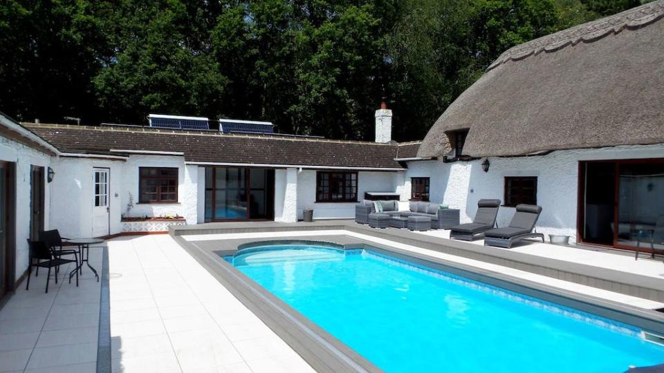 <p>This beautiful thatched cottage with a pool on the Dorset/Hampshire border is ideal for lovers of the outdoors. It's made for big groups of 22 and you'll find plenty of spaces to relax together, from the outdoor swimming pool to the eight-person <a href="https://www.womenshealthmag.com/uk/fitness/fitness-holidays/g28585380/best-airbnbs-with-hot-tubs/" rel="nofollow noopener" target="_blank" data-ylk="slk:hot tub;elm:context_link;itc:0;sec:content-canvas" class="link ">hot tub</a>. The beautiful barn is perfect for trying out your favourite healthy recipes on the gang and there are outdoor outdoor games like football, croquet and badminton to enjoy getting active in a fun style.</p><p><strong>Sleeps:</strong> 22</p><p><strong>Pets: </strong>Yes</p><p><strong>Bring:</strong> A <a href="https://www.womenshealthmag.com/uk/fitness/strength-training/a26959575/health-headlines-thirty-three/" rel="nofollow noopener" target="_blank" data-ylk="slk:meditation;elm:context_link;itc:0;sec:content-canvas" class="link ">meditation</a> cushion. The outdoor space is stunning and there's even a fish pond with Koi.</p><p><strong>Price: </strong>3 nights from £2,958</p><p><strong>Available from: </strong><a href="https://go.redirectingat.com?id=127X1599956&url=https%3A%2F%2Fwww.homeaway.co.uk%2Fp8310223&sref=https%3A%2F%2Fwww.womenshealthmag.com%2Fuk%2Ffitness%2Ffitness-holidays%2Fg33559308%2Fcottages-with-pools%2F" rel="nofollow noopener" target="_blank" data-ylk="slk:HomeAway;elm:context_link;itc:0;sec:content-canvas" class="link ">HomeAway</a></p>