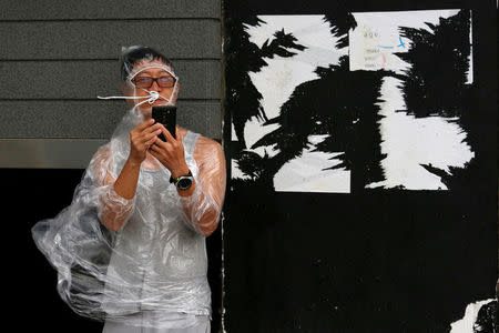 A man uses a smartphone under strong winds near a waterfront as Typhoon Haima approaches in Hong Kong, China, October 21, 2016 . REUTERS/Bobby Yip